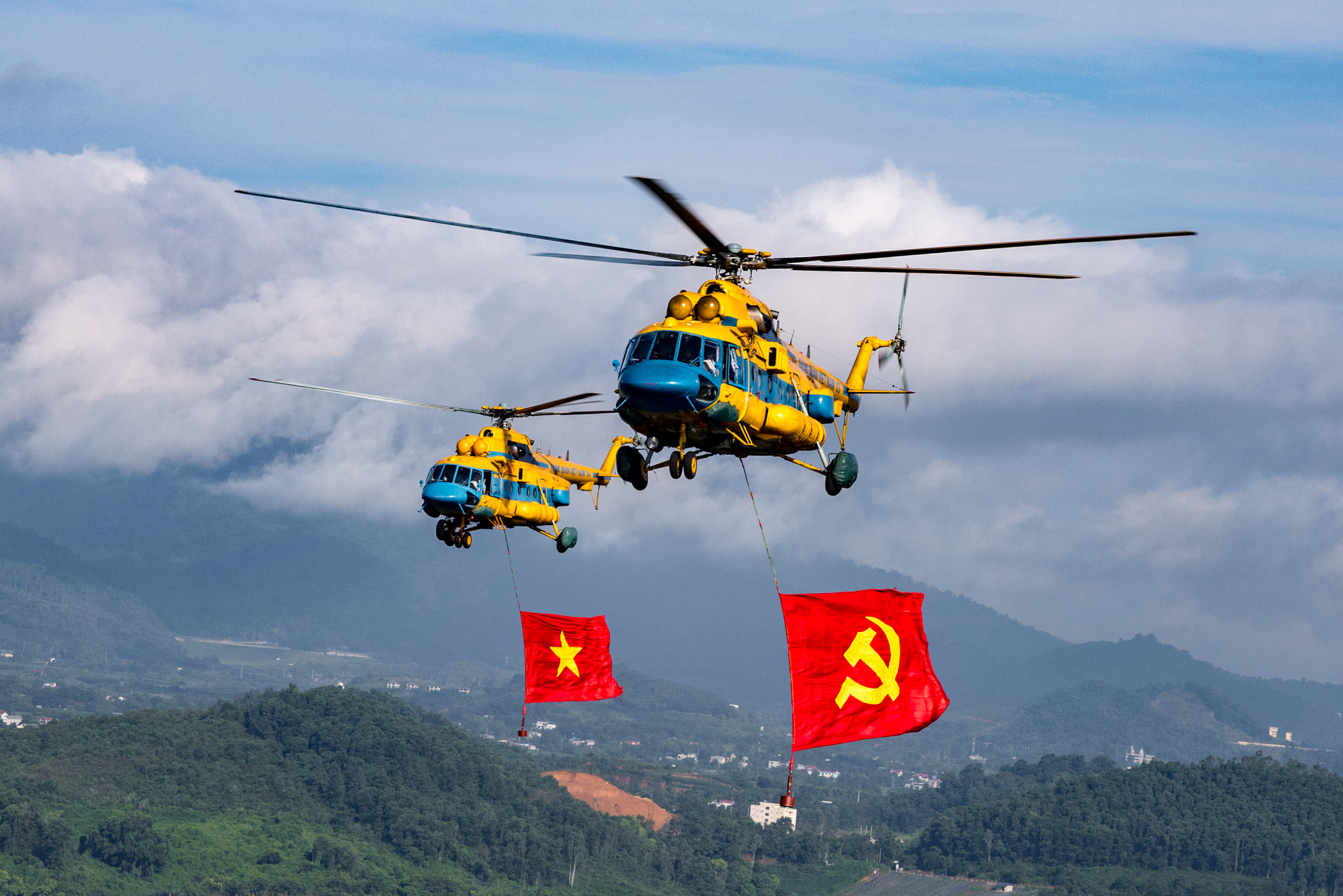Helicopters fly to train formations flying Party and national flags