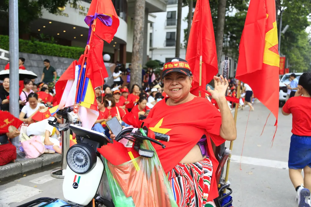 Although the old lady is physically disabled, she still joins the crowd of people watching and practicing. Photo: HA NGUYEN
