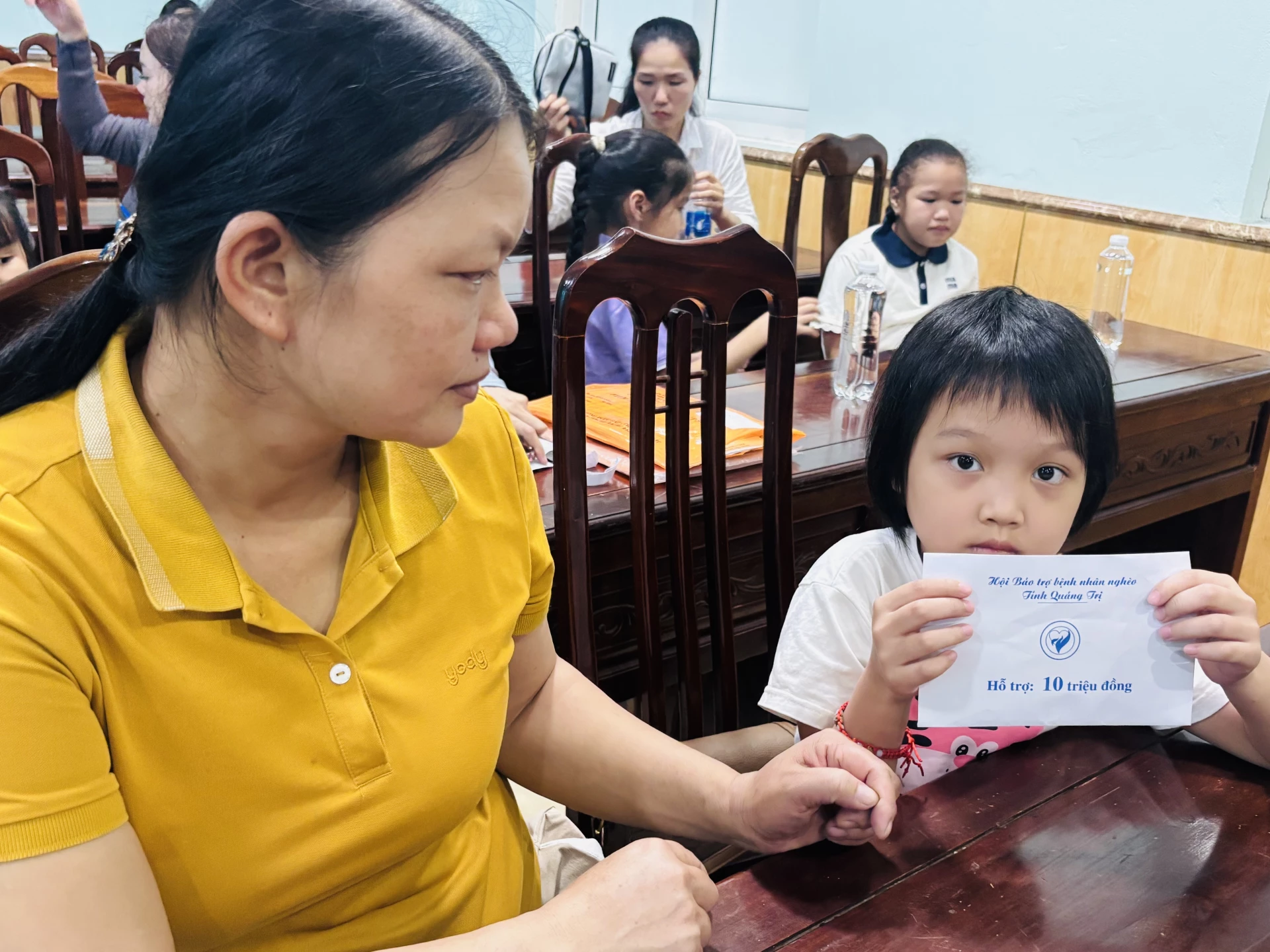 Cháu Phan Bảo Châu (ung thư máu) cùng mẹ nhận hỗ trợ kinh phí điều trị tại chương trình - Ảnh: Kim Hoa