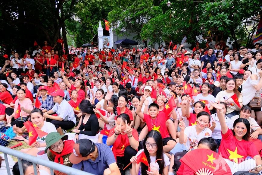 សមុទ្រ​មនុស្ស​មាន​ទង់ជាតិ​ពណ៌​ក្រហម​ដោយ​អន្ទះសា​រង់ចាំ​មើល​ការ​ហាត់សម​ក្បួន​ដង្ហែ​ជា​លើក​ទី​ពីរ។