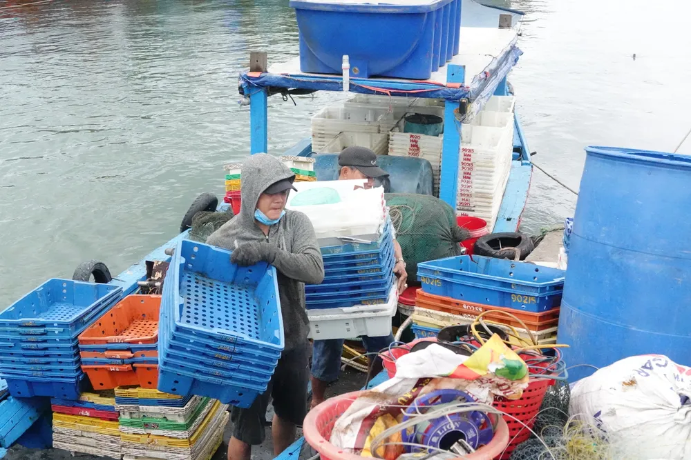 Ngư dân bốc vác đồ đạc lên bờ. Ảnh: XUÂN QUỲNH