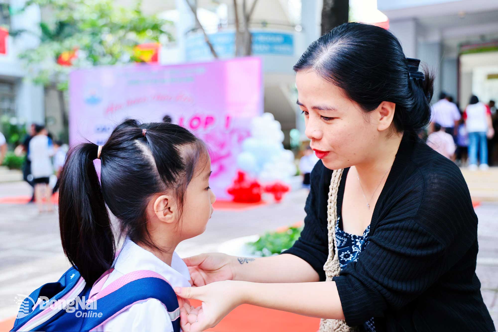 ឪពុកម្តាយកែកអាវរបស់កូនស្រីគាត់នៅថ្ងៃចូលរៀនដំបូង។ រូបថត៖ Cong Nghia