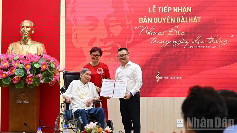 និពន្ធនាយក Le Quoc Minh ទទួលសៀវភៅចម្រៀងរបស់តន្ត្រីករ Pham Tuyen ពីគ្រួសារតន្ត្រីករ។ (រូបថត៖ THANH DAT)