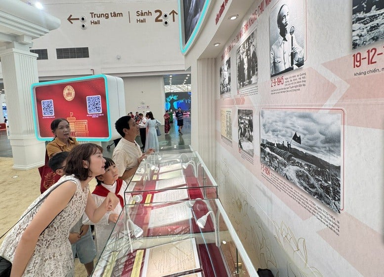 A parent introduces to her daughter a historical photo of September 2, 1945 at Ba Dinh Square, Hanoi, President Ho Chi Minh reading the Declaration of Independence on behalf of the provisional government, giving birth to the Democratic Republic of Vietnam - Photo: VGP/GH