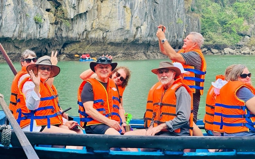 Khách quốc tế trải nghiệm khám phá vịnh Hạ Long bằng loại thuyền truyền thống trong tour du lịch Việt Nam.