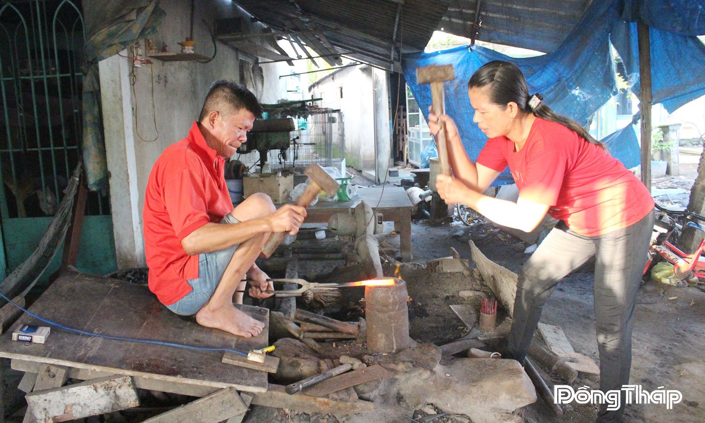 Vợ chồng anh Lê Văn Sắt (xã Mỹ An Hưng) dùng búa đập liên tục vào thanh sắt để tạo hình  cho sản phẩm rèn.