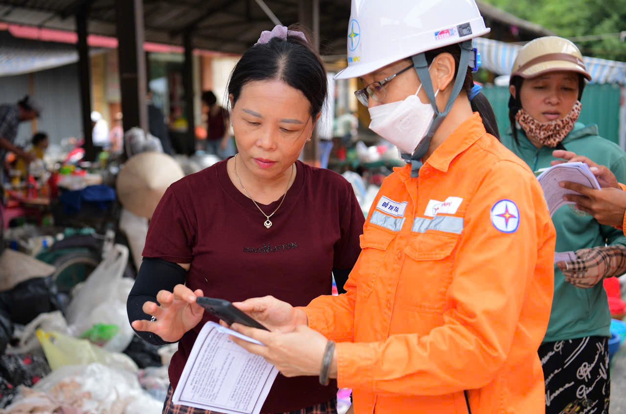 Nhân viên Công ty Điện lực Ninh Bình hướng dẫn người dân xã Vạn Thắng thanh toán tiền điện không dùng tiền mặt. (Ảnh: Trường Giang)
