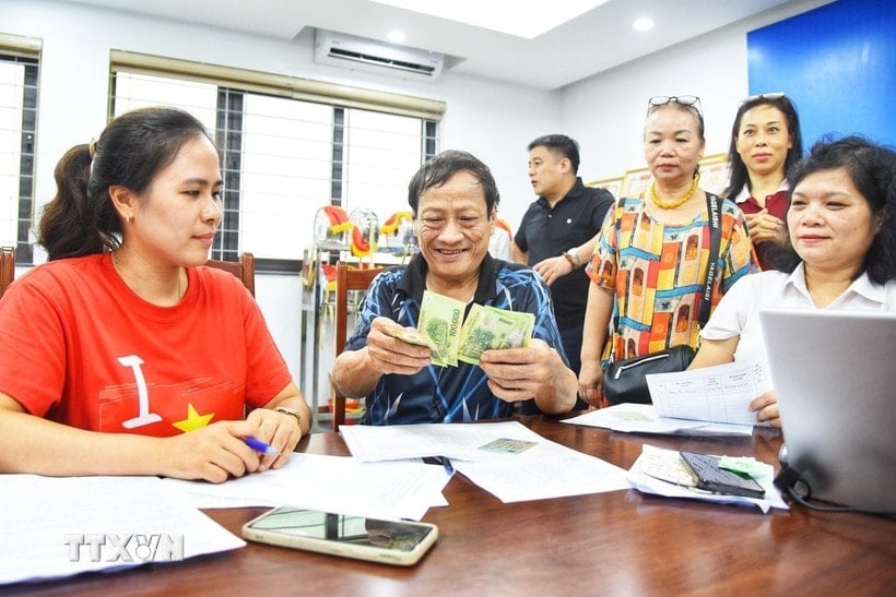 ប្រជាជន​មក​ចុះឈ្មោះ​ទទួល​អំណោយ​នៅ​ចំណុច​ទូទាត់​ប្រាក់​ក្នុង​វួដ Bo De (ហាណូយ)។ (រូបថត៖ Minh Quyet/VNA)
