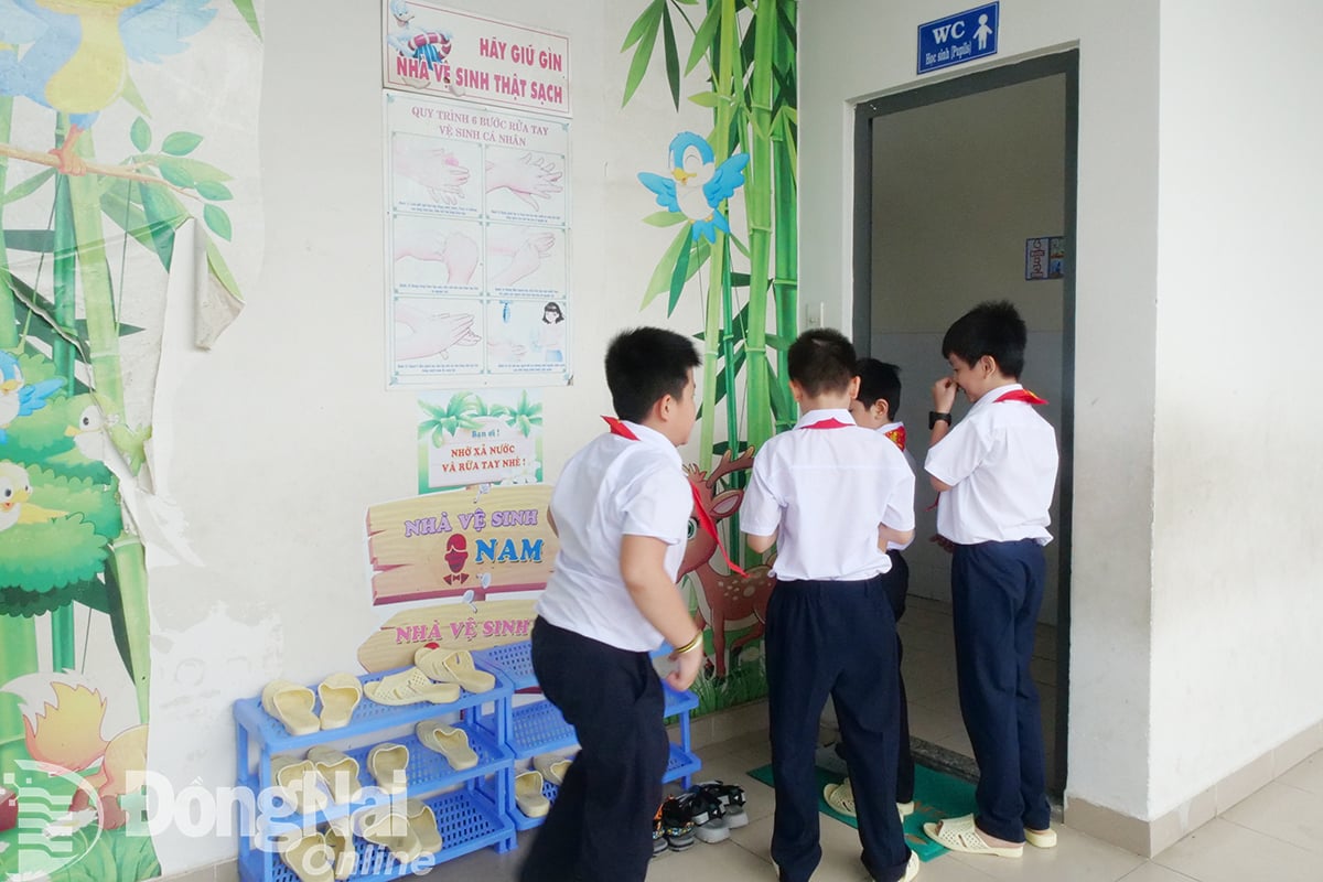Học sinh Trường Tiểu học Nguyễn An Ninh (phường Tam Hiệp) thay dép nhựa trước khi vào nhà vệ sinh. Ảnh:An Yên