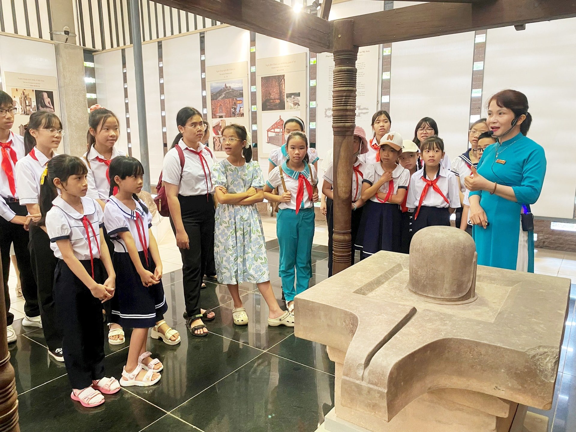 ចូលរួមក្នុងកម្មវិធីអប់រំបេតិកភណ្ឌ សិស្សានុសិស្សបានស្តាប់ការពន្យល់អំពីវត្ថុបុរាណវប្បធម៌ចាមនៅបរិវេណប្រាសាទ My Son ។ រូបថត៖ VINH LOC