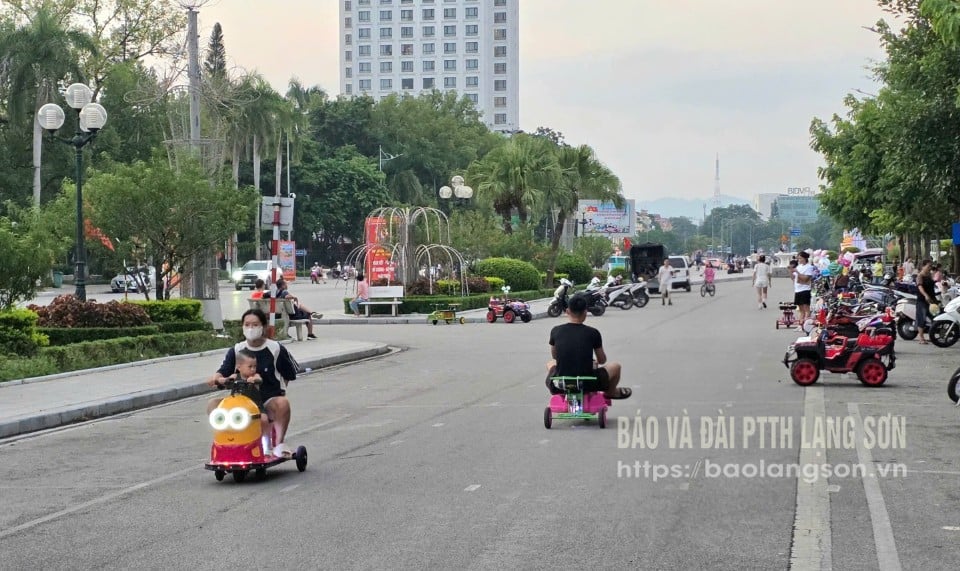 Ảnh lớn:  Nhiều phụ huynh đi xe điện đồ chơi dưới lòng đường Hùng Vương (ảnh chụp 17 giờ30 phút ngày 14/9/2025) Ảnh nhỏ:  Các loại xe điện đồ chơi bày tràn lan tại đường Hùng Vương, phường Lương Văn Tri