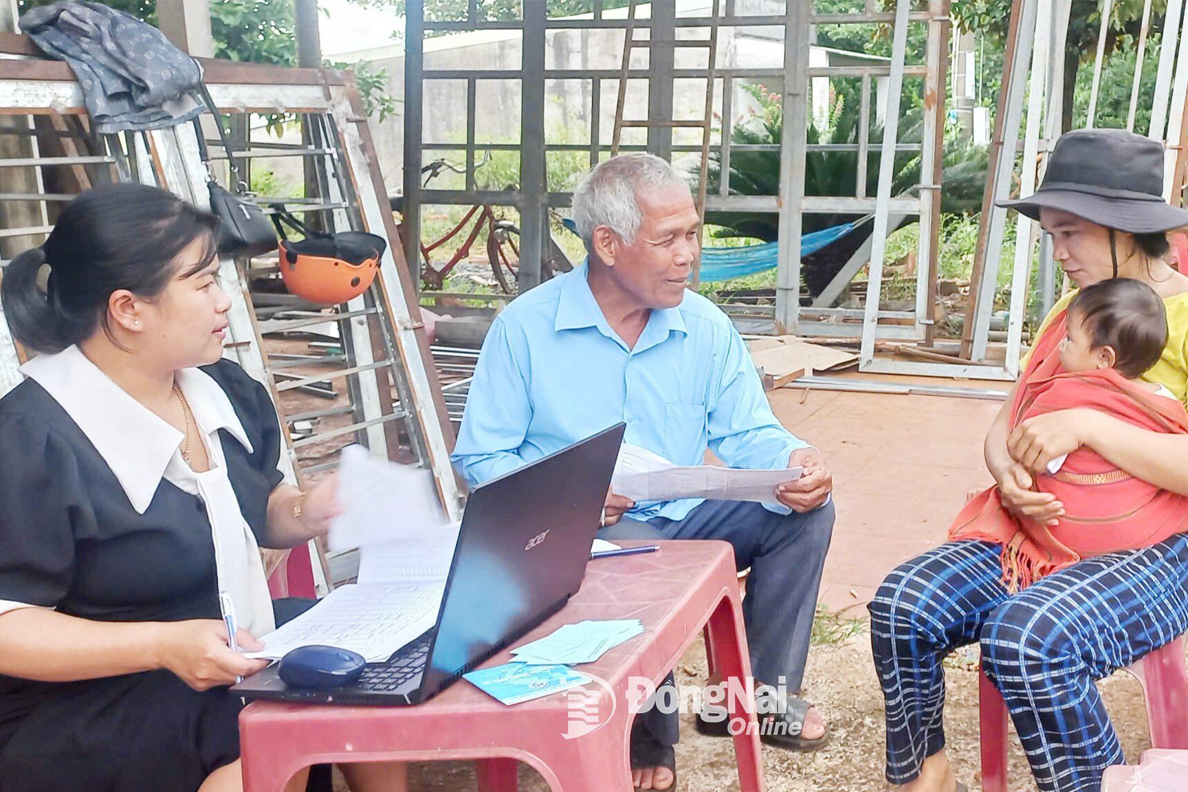 Ông Điểu Đé (thôn Hai Căn, xã Phú Nghĩa, tỉnh Đồng Nai) hỗ trợ nhân viên Trạm Y tế xã tiếp nhận và lấy thông tin của người dân đưa con đi tiêm chủng. Ảnh: C.T.V