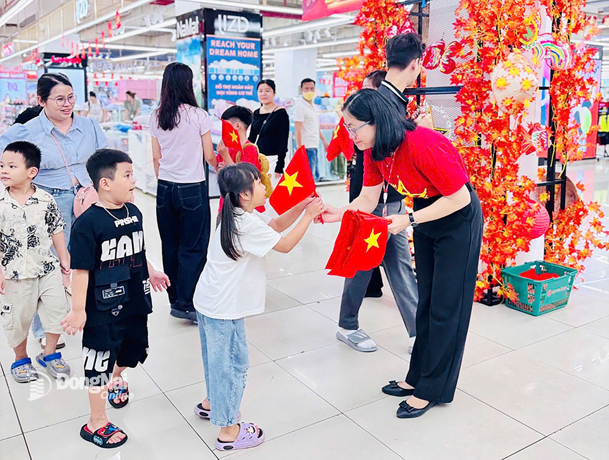 El personal de Lotte Mart Dong Nai entrega banderas rojas con estrellas amarillas a los clientes que vienen a comprar al supermercado. Foto: D.T.