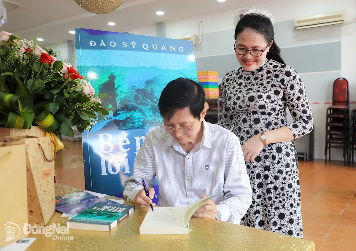 អ្នកនិពន្ធ Dao Sy Quang នាយកដ្ឋានអក្សរសាស្ត្រ សមាគមអក្សរសិល្ប៍ និងសិល្បៈ Dong Nai ចុះហត្ថលេខាលើសៀវភៅសម្រាប់អ្នកអានក្នុងពិធីសម្ពោធប្រលោមលោក On the Other Side of the Promise។ រូបថត៖ My Ny