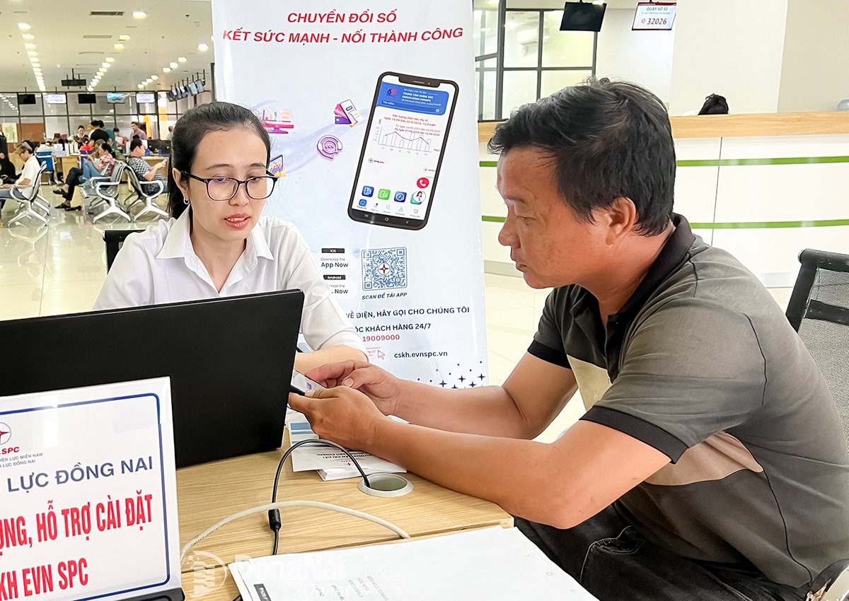 Ứng dụng CSKH EVNSPC tích hợp nhiều tính năng về tra cứu chỉ số điện, thanh toán tiền điện trực tuyến. Trong ảnh: Người dân được nhân viên của Công ty Điện lực Đồng Nai hỗ trợ, hướng dẫn cài đặt ứng dụng CSKH EVNSPC tại Trung tâm Phục vụ hành chính công tỉnh Đồng Nai. Ảnh: Hải Quân

