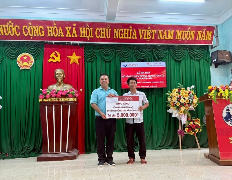 Ông Lê Thành Nam - Phó Giám đốc Agribank Chi nhánh Quy Nhơn (bên trái) trao quà cho Tổ đồng quản lý bảo vệ nguồn lợi thủy hải sản xã Nhơn Châu