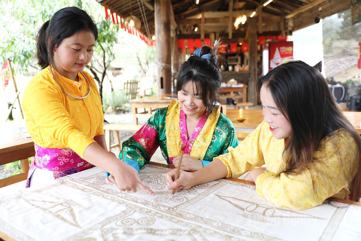 Du khách trải nghiệm vẽ tranh sáp ong cùng với với cô giái Mông chủ nhà.