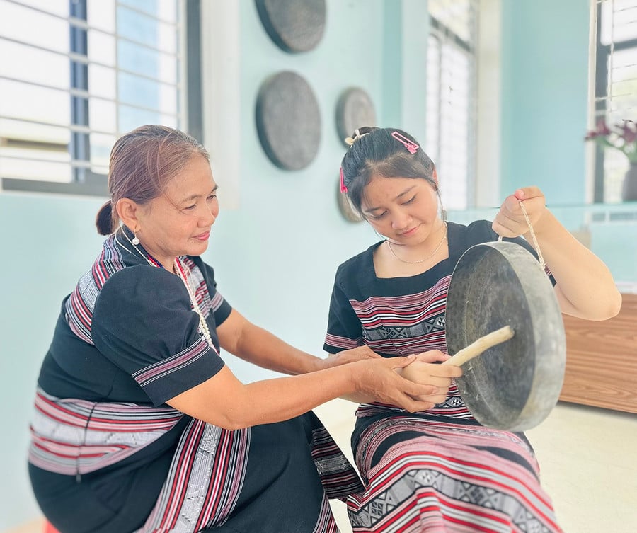 Bà Đinh Thị Tuyết (bìa trái) hướng dẫn em Đinh Thị Kim Ngân cách đánh chinh tía (chiêng 5).