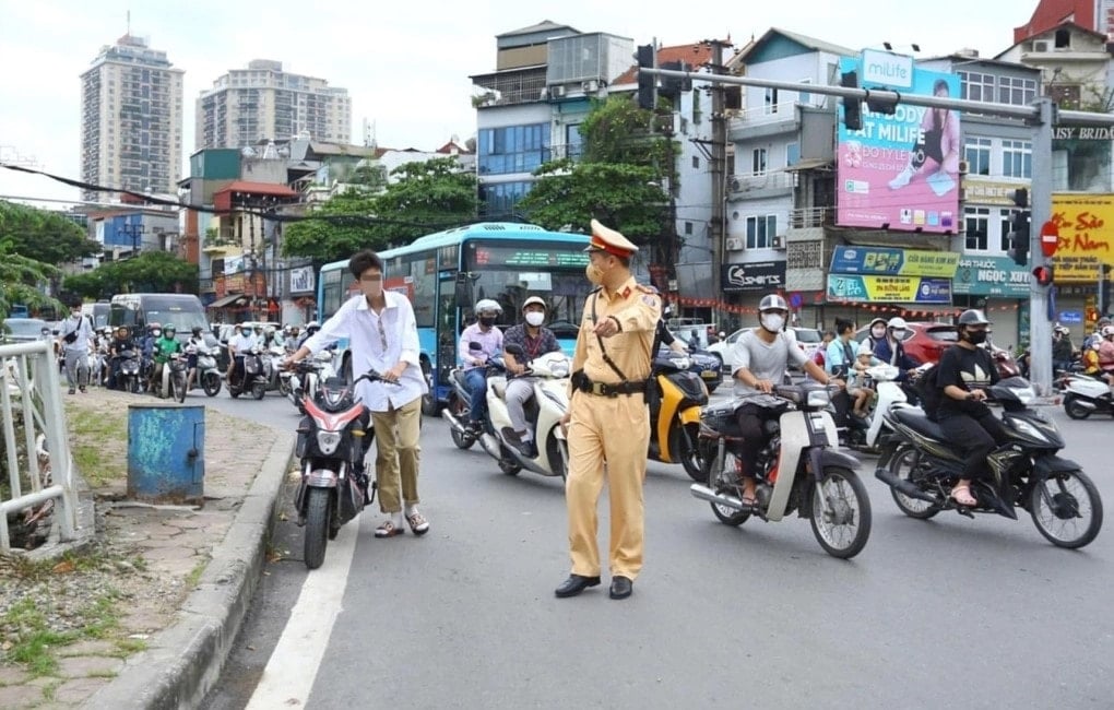 A traffic police officer from Highway 3, Hanoi City Police, checks a student riding an electric motorbike without wearing insurance. Anh Viet An.jpg