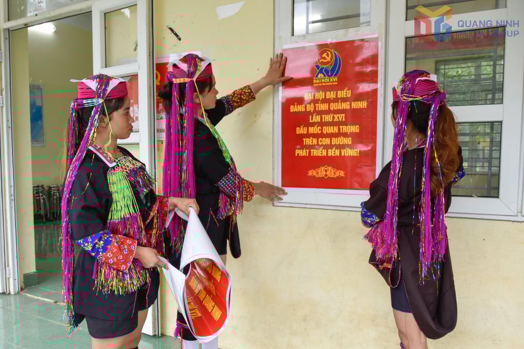 Đảng viên thôn Nà Nhái, xã Bình Liêu, dán áp phích tuyên truyền trực quan chào mừng hội.