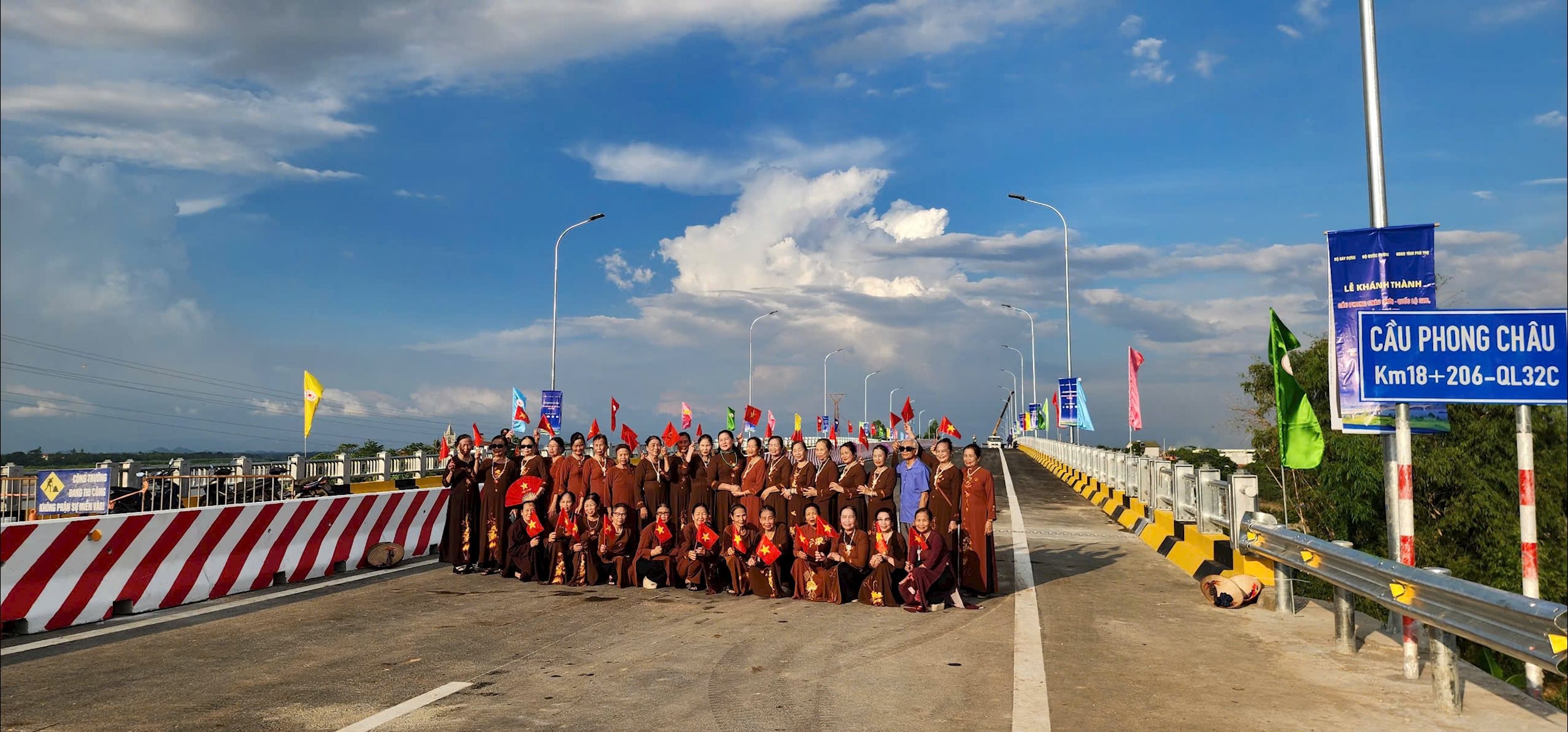 ຜູ້​ເຖົ້າ​ແກ່​ທີ່​ມີ​ທຸງ​ສີ​ແດງ​ທີ່​ມີ​ຮູບ​ດາວ​ເຫຼືອງ​ຢູ່​ໃນ​ມື​ໄດ້​ອອກ​ມາ​ເບິ່ງ​ຂົວ​ແລະ​ຖ່າຍຮູບ​ໂດຍ​ກົງ.
