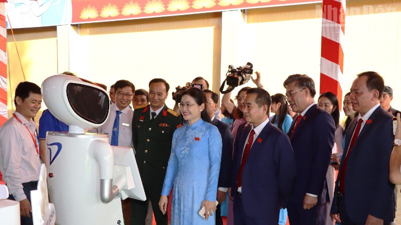 Delegates attending the 1st Dong Nai Provincial Party Congress, term 2025-2030 interact with a robot model that performs functions like humans.