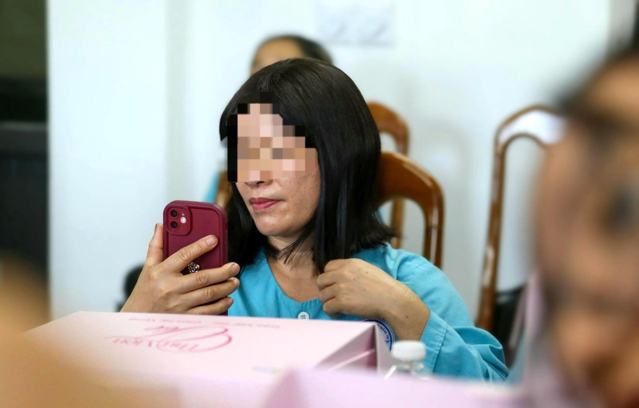 Bà N. đưa điện thoại lên soi, ngắm nghía bản thân với bộ tóc mới được trao tặng.