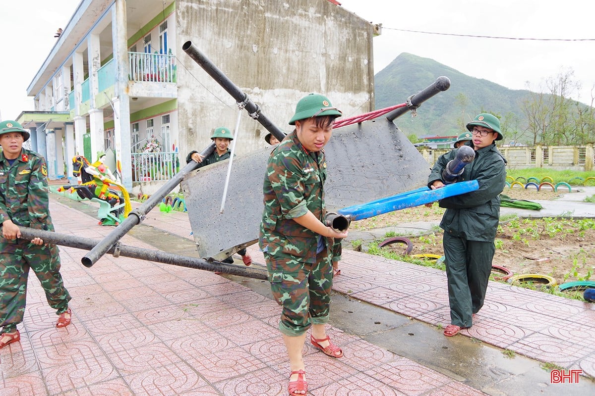 Cán bộ, chiến sĩ Trung đoàn 841 cùng dân quân di chuyển vật dụng hư hỏng tại Trường THCS Tân Vịnh, phường Trần Phú