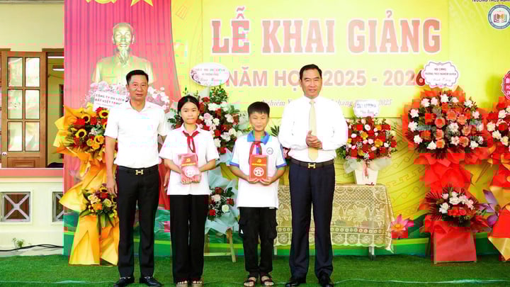 Ông Tạ Hữu Thọ, Bí thư Đảng ủy xã Thượng Phúc (bên phải) tặng quà cho các em có hoàn cảnh khó khăn trường THCS Nghiêm Xuyên nhân dịp khai giảng. (Ảnh: Hương Phạm)