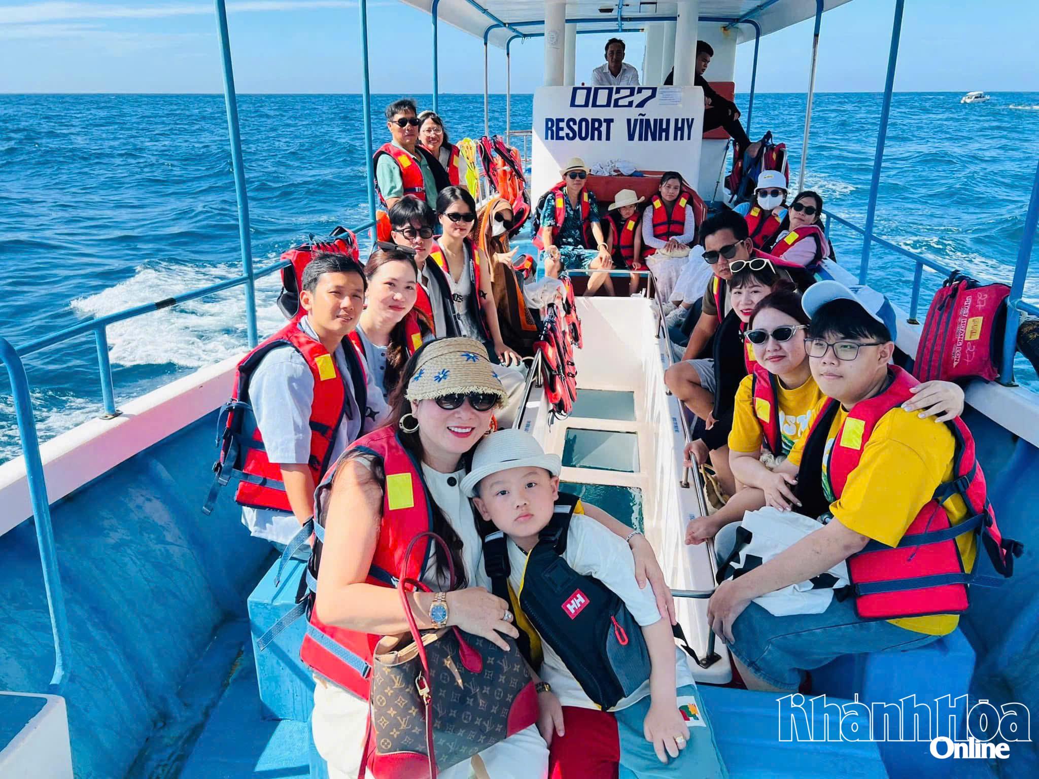 Pelancong mengambil lawatan bot berdasar kaca untuk melihat terumbu karang di Teluk Vinh Hy.