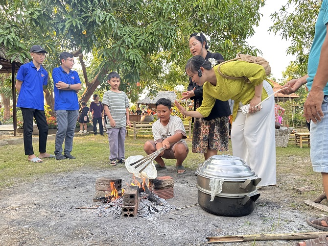 +ảnh 2: Du khách trải nghiệm làm bánh phồng tại không gian “Đêm Tân Thuận Tây” ở Đồng Tháp. Ảnh: An Xuyên.