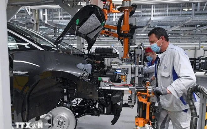 Trabajadores en una fábrica de automóviles en Zwickau, Alemania. (Foto: AFP/VNA) Công nhân làm việc tại một nhà máy sản xuất ôtô ở Zwickau (Đức). (Ảnh: AFP/TTXVN)