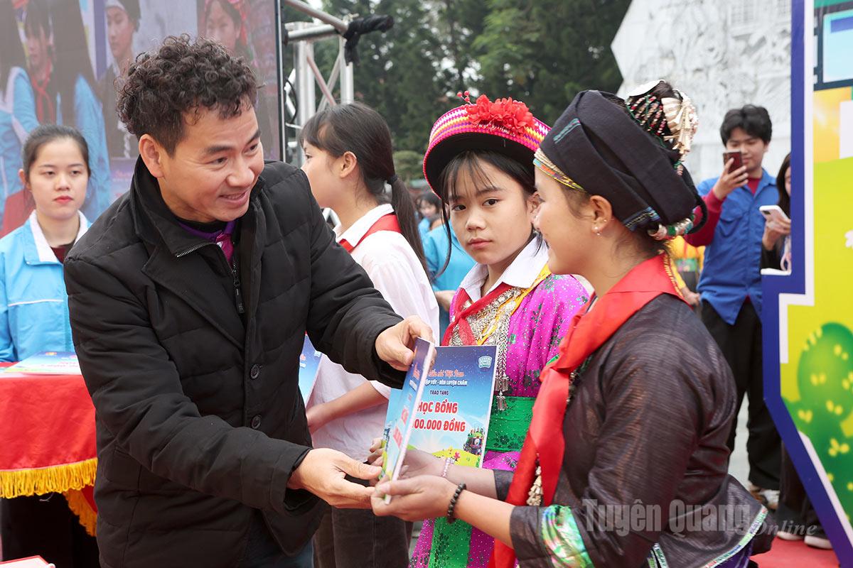 L'artiste du peuple Nguyen Xuan Bac, directeur du département des arts du spectacle du ministère de la Culture, des Sports et du Tourisme, remet des bourses d'études et des cadeaux du Têt à des enfants.
