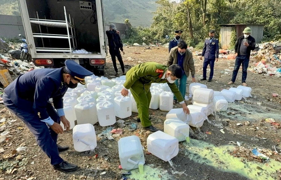 Polizeibeamte beschlagnahmen und vernichten nicht registrierten Alkohol in Lao Cai.jpg