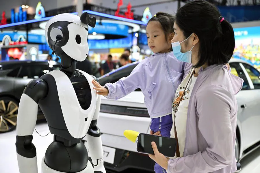 I consumatori interagiscono con robot dotati di intelligenza artificiale alla Fiera Internazionale dei Consumatori della Cina. Foto: XINHUA