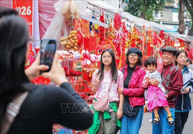 Människor bevarar minnen på Hang Luocs blomstermarknad (Hanoi) dagarna före Tet. Foto: Hoang Hieu/TTXVN.