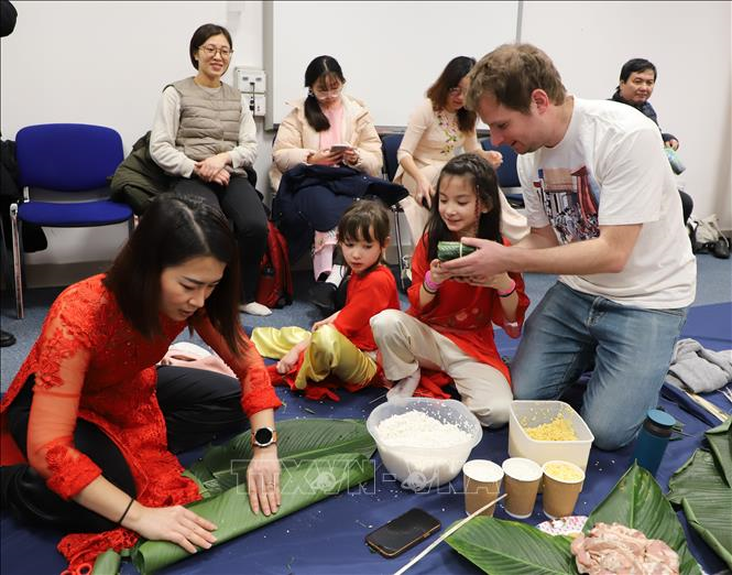 Một gia đình Việt - Anh hào hứng tham gia cuộc thi gói bánh chưng tại lễ hội. Ảnh: TTXVN