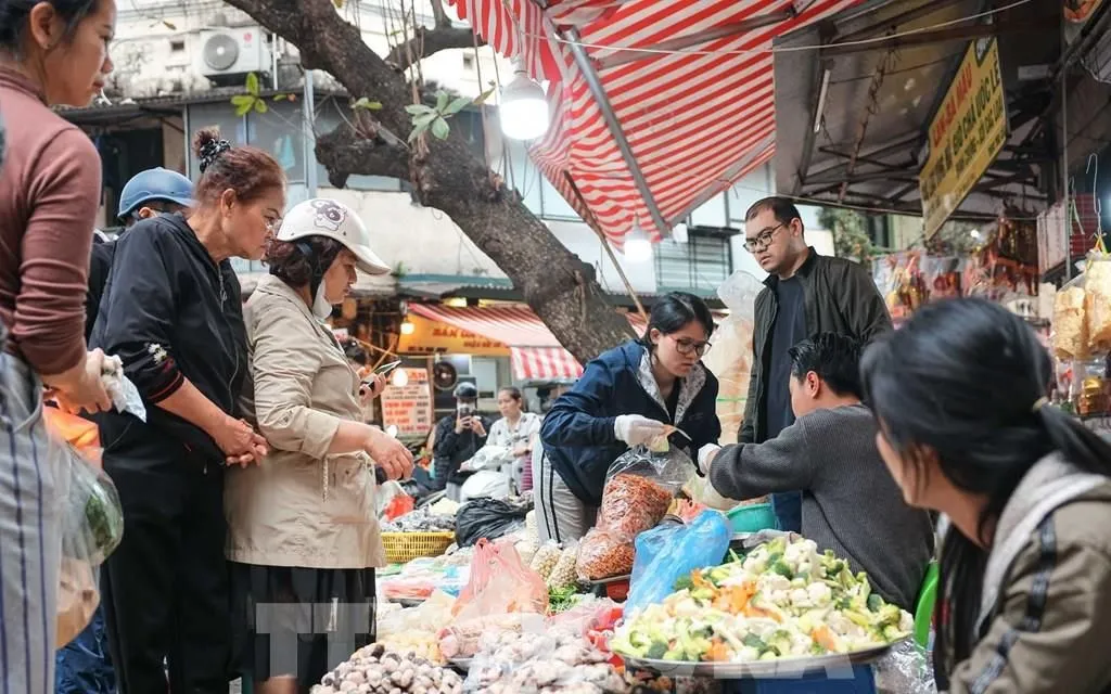 Persone che fanno acquisti in un mercato tradizionale. Foto: Hoang Hieu - VNA