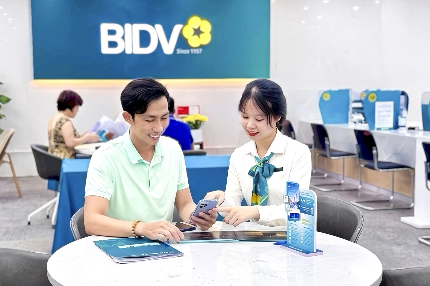 A bank employee advises and assists customers on how to secure their mobile banking application.