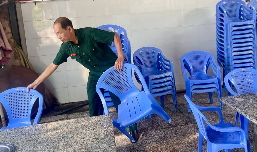 Il veterano Ta Kim Bac sta sparecchiando tavoli e sedie, preparandosi ad aprire il suo ristorante.