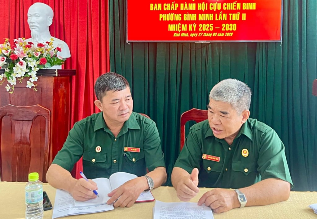 Il veterano Nguyen Ngoc Con (a destra) discute del suo lavoro con il presidente dell'Associazione dei veterani del distretto di Binh Minh.