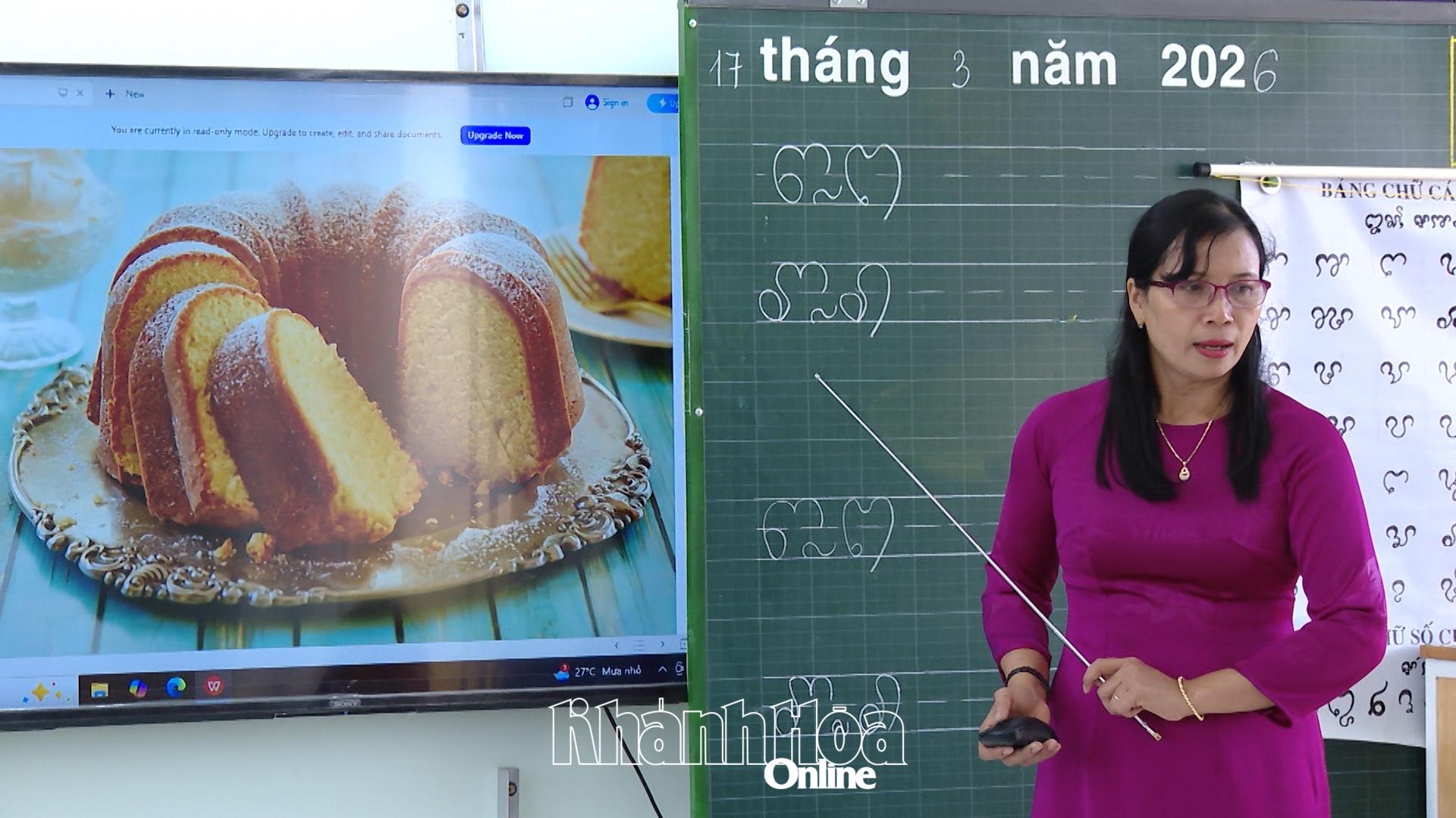 The teacher guides the students in writing the Cham script, incorporating illustrative images into the lesson.