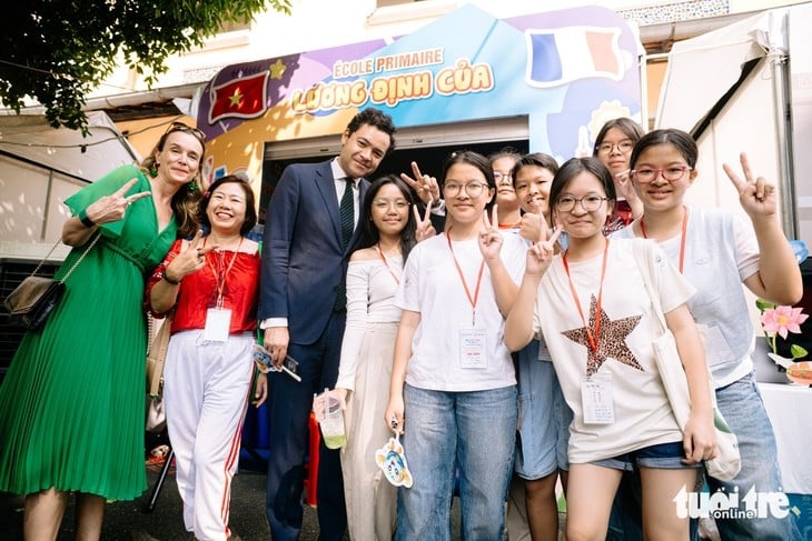 Tổng lãnh sự Pháp tại TP.HCM Etienne Ranaivoson cùng bà Anne Laure Vincent, Tùy viên hợp tác giáo dục, Viện Pháp tại Việt Nam, chụp ảnh cùng các bạn học sinh tham gia Ngày hội Pháp ngữ 2026