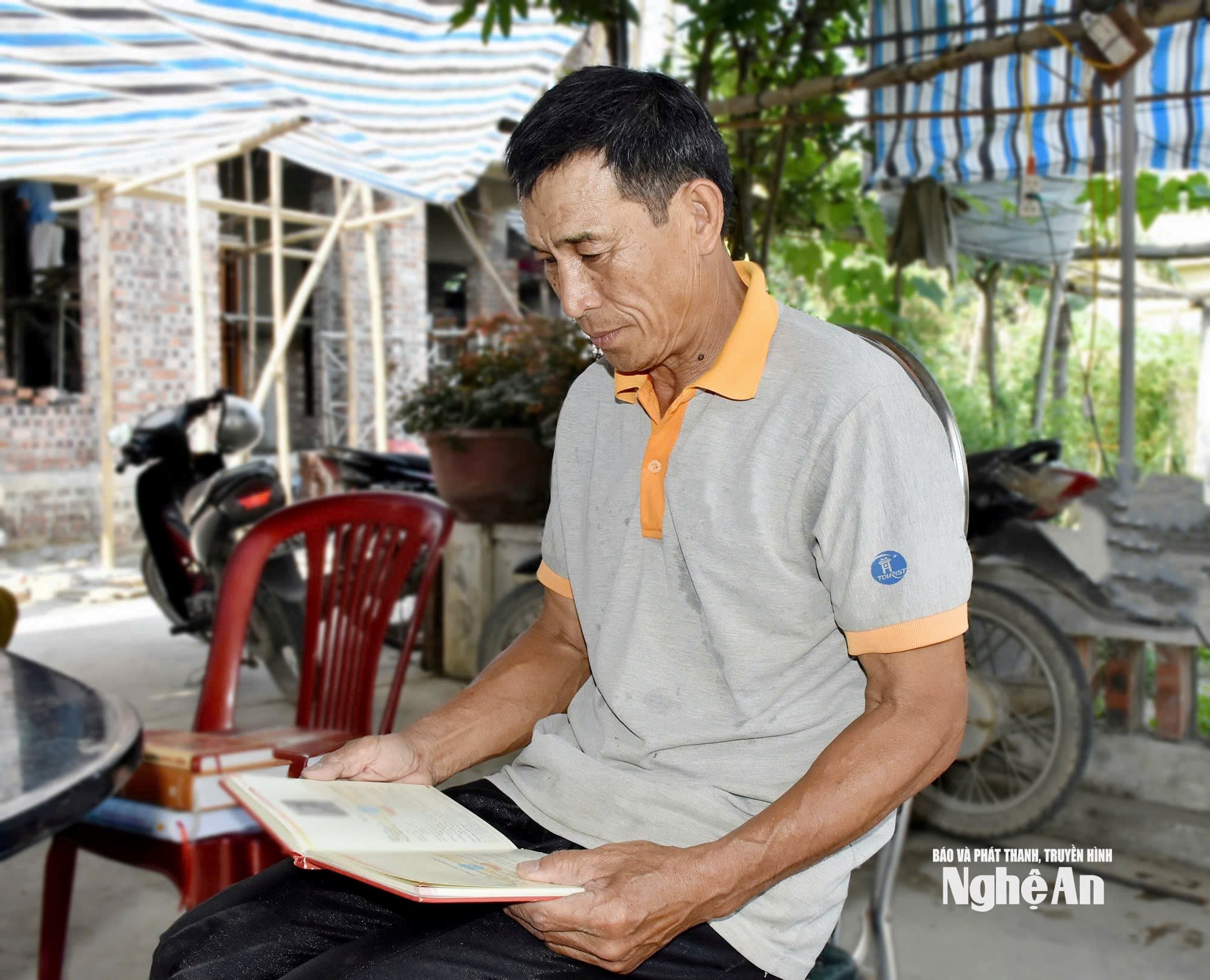 Pan Ngo Duc Phuong si prohlíží dokumenty o hrdinských činech svého bratra, Ngo Duc Maie, hrdiny a mučedníka. Foto: Cong Kien.