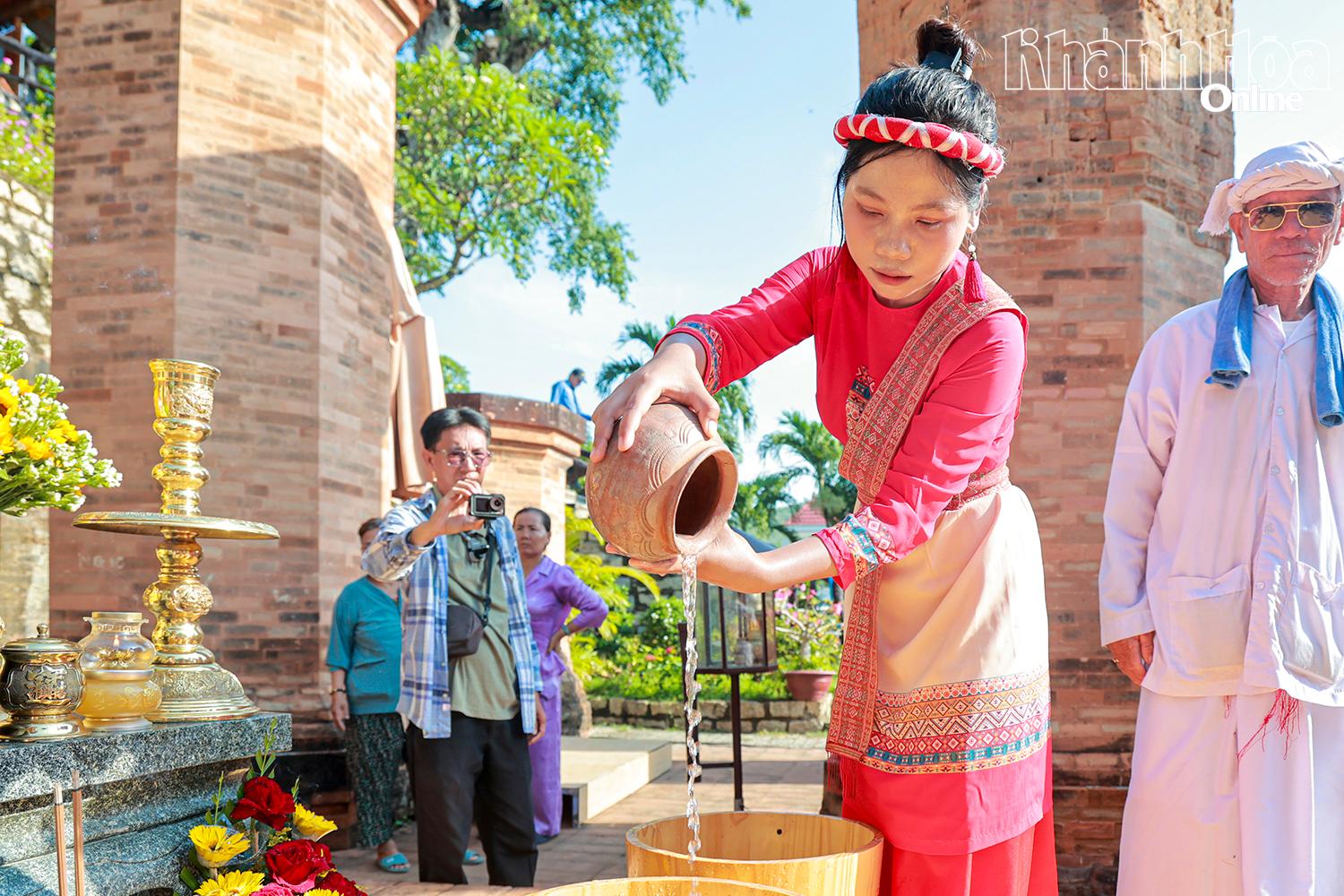 หญิงสาวชาวจามเทน้ำจากหม้อดินเผาลงในถัง