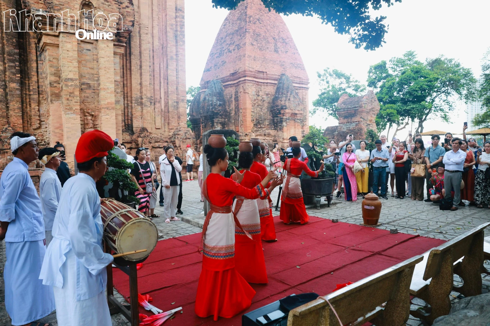 Toeristen bekijken traditionele Cham-kunstvoorstellingen bij de historische Po Nagar Cham-torens.