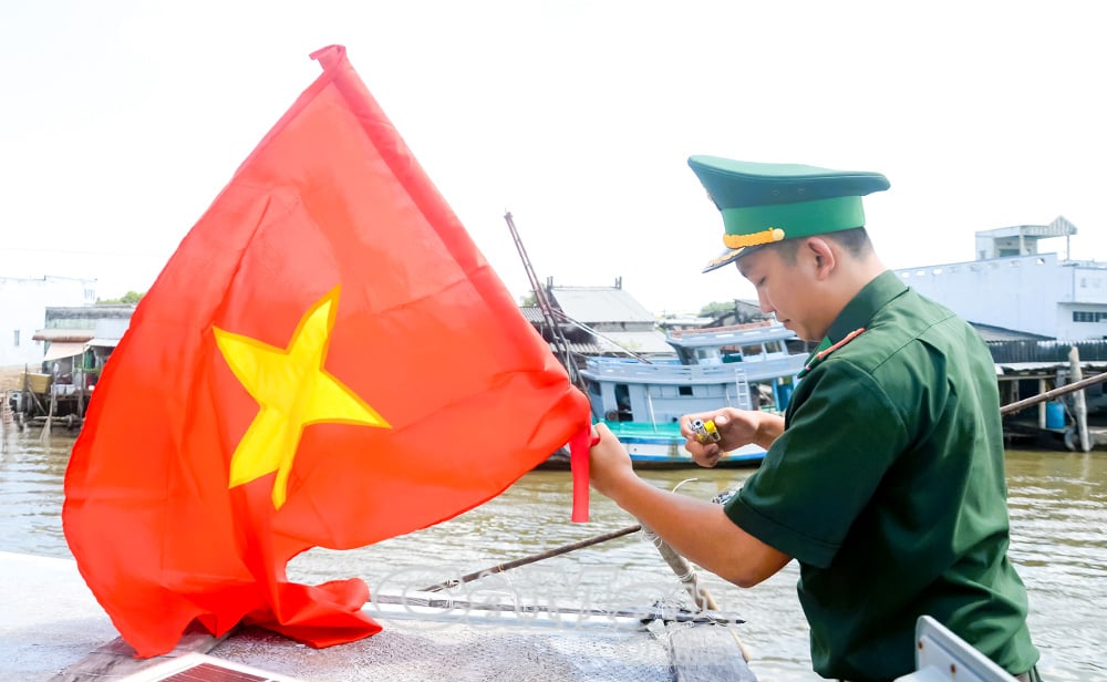 Para petugas dari Pos Penjaga Perbatasan Cai Doi Vam mengganti bendera nasional di perahu nelayan yang hendak melaut.