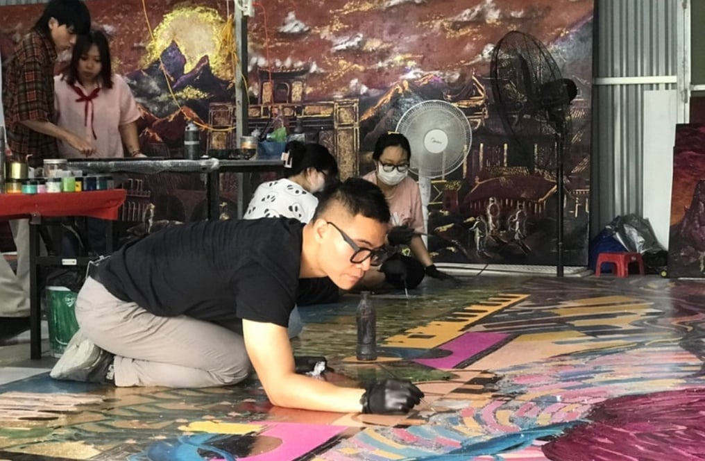 アーティストのチュ・ニャット・クアンが、展覧会で展示される大型漆絵「ホーおじさんが独立宣言を読む」に銀箔を貼っている。写真:ティエン・クオン。 Họa sĩ Chu Nhật Quang thếp bạc trên bức tranh sơn mài khổ lớn 'Bác Hồ đọc Tuyên ngôn Độc lập' sẽ trưng bày tại triển lãm. Ảnh: Tiến Cường.