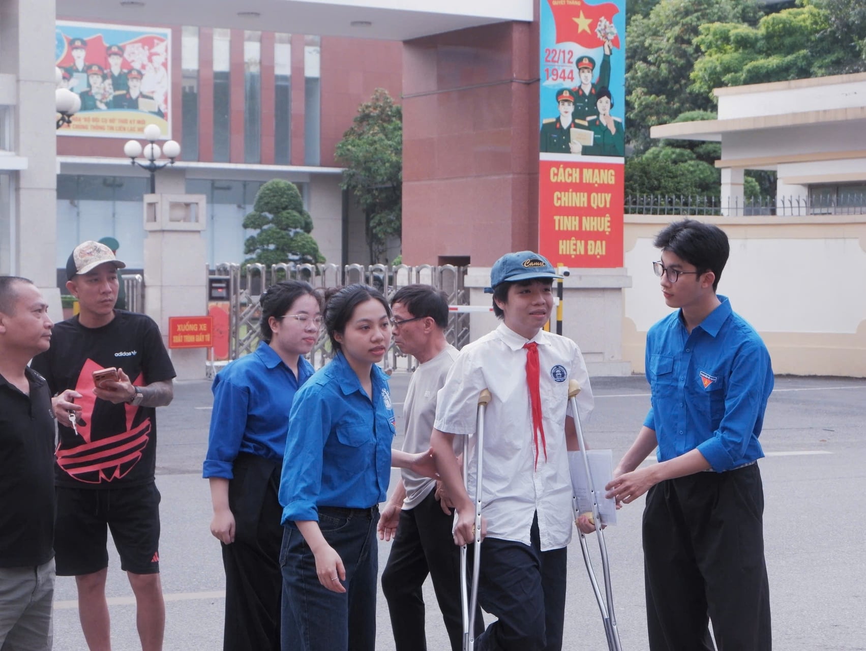 Sinh viên tình nguyện hỗ trợ thí sinh bị đau chân vào điểm thi tại Trường THCS Nguyễn Trãi (phường Giảng Võ). Ảnh: Phú Quang.