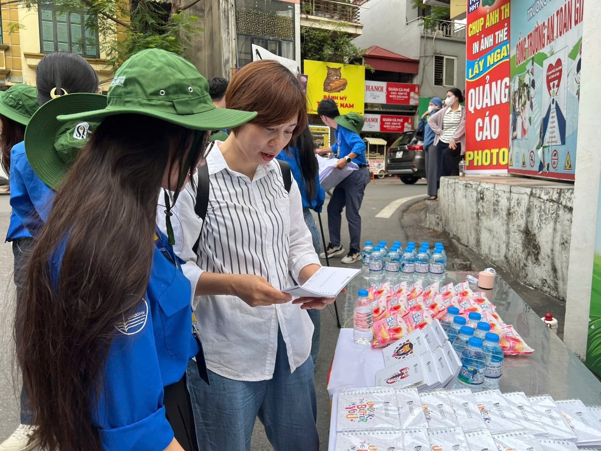 Tình nguyện viên phường Ngọc Hà hướng dẫn phụ huynh tại điểm thi lớp 10 THPT công lập. Ảnh: Lan Chi.